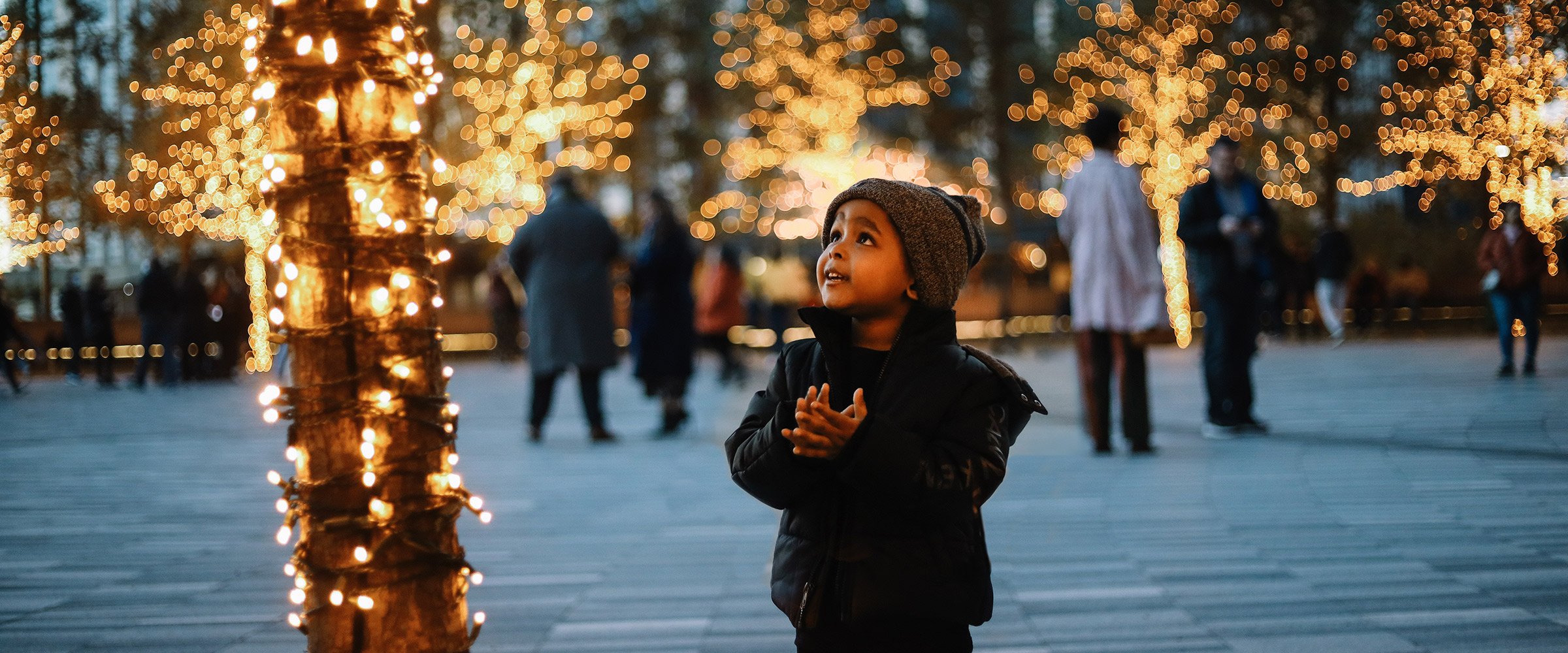 Little boy in NYC surrounded by holiday lights